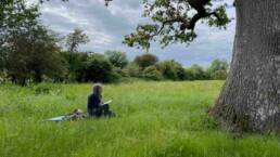 photo of Ruth Broadbent sitting on log in grass under oak tree